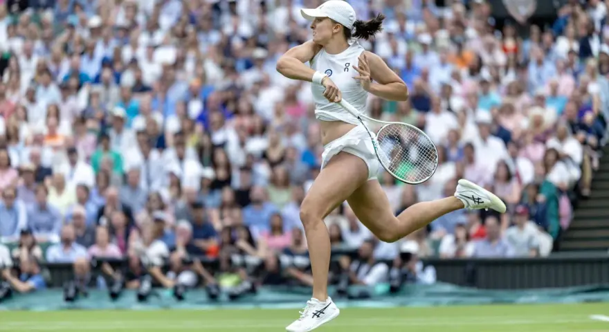 Tenisistka w akcji na korcie podczas WTA Berlin. Dynamiczny ruch, rakieta w dłoni, tłum kibiców na trybunach.