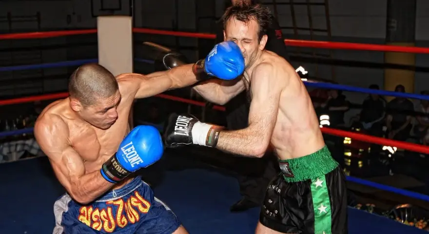 Dwóch zawodników wagi średniej UFC walczy w ringu. Jeden z nich wyprowadza cios, drugi blokuje.