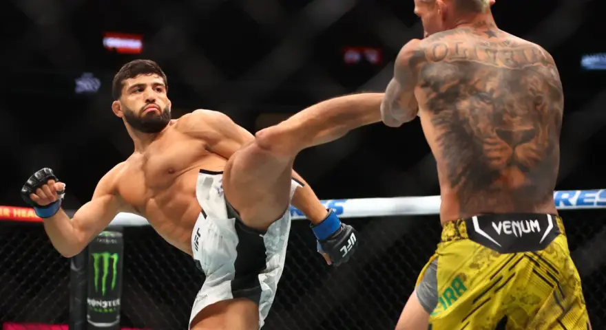 Waga półśrednia UFC: zawodnik wykonuje wysokie kopnięcie, jego przeciwnik z tatuażem lwa na plecach blokuje cios.
