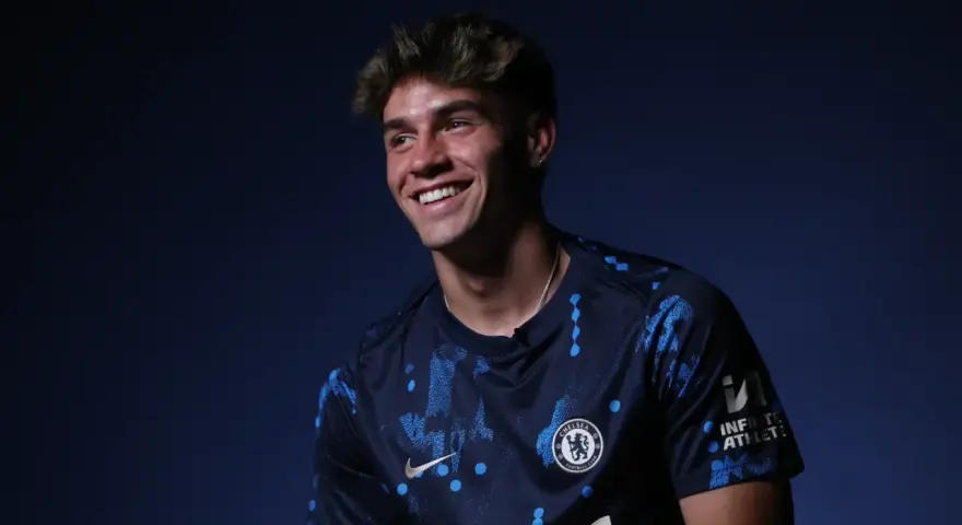 Uśmiechnięty Marc Guiu w ciemnogranatowej koszulce Chelsea z niebieskimi wzorami.