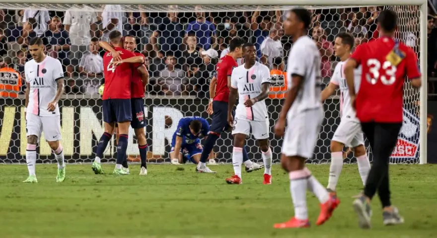 Piłkarze PSG i Lille świętują po meczu. Jeden z zawodników Lille klęczy na boisku.