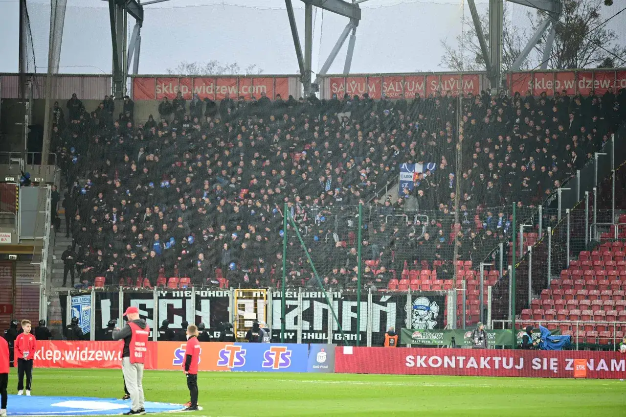 Tłum kibiców na trybunach podczas meczu Widzew Łódź – Lech Poznań. Widać transparenty z nazwami klubów i logotypami sponsorów.