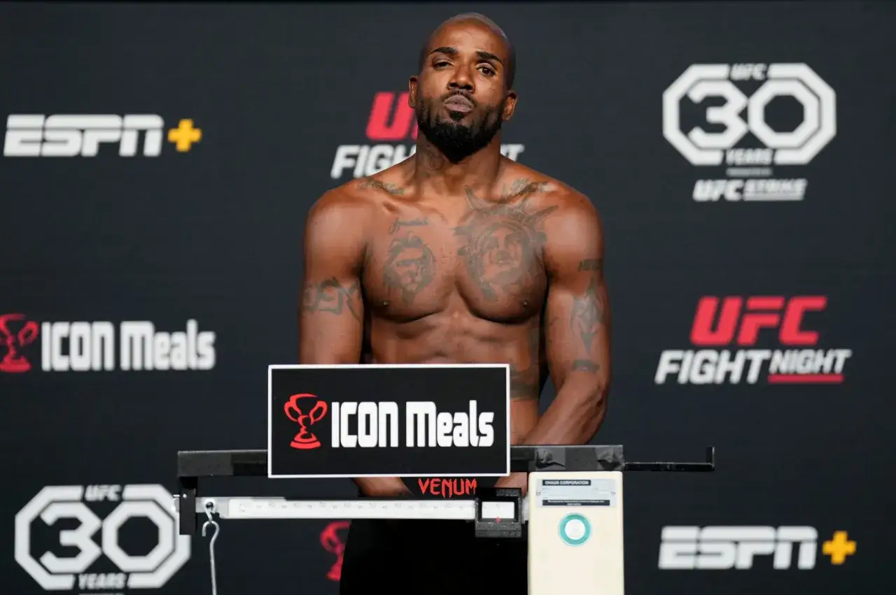 Zawodnik kategorii lekkiej UFC na wadze, z tatuażami na klatce piersiowej i ramionach, na tle logotypów UFC Fight Night i ESPN+.