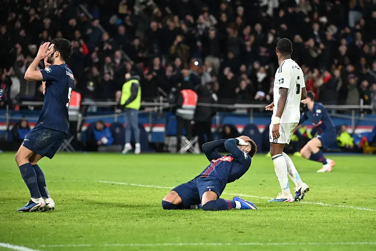 Piłkarze PSG i Lille po przegranym meczu. Neymar klęczy z rękami na twarzy, a jego kolega z drużyny trzyma się za głowę.