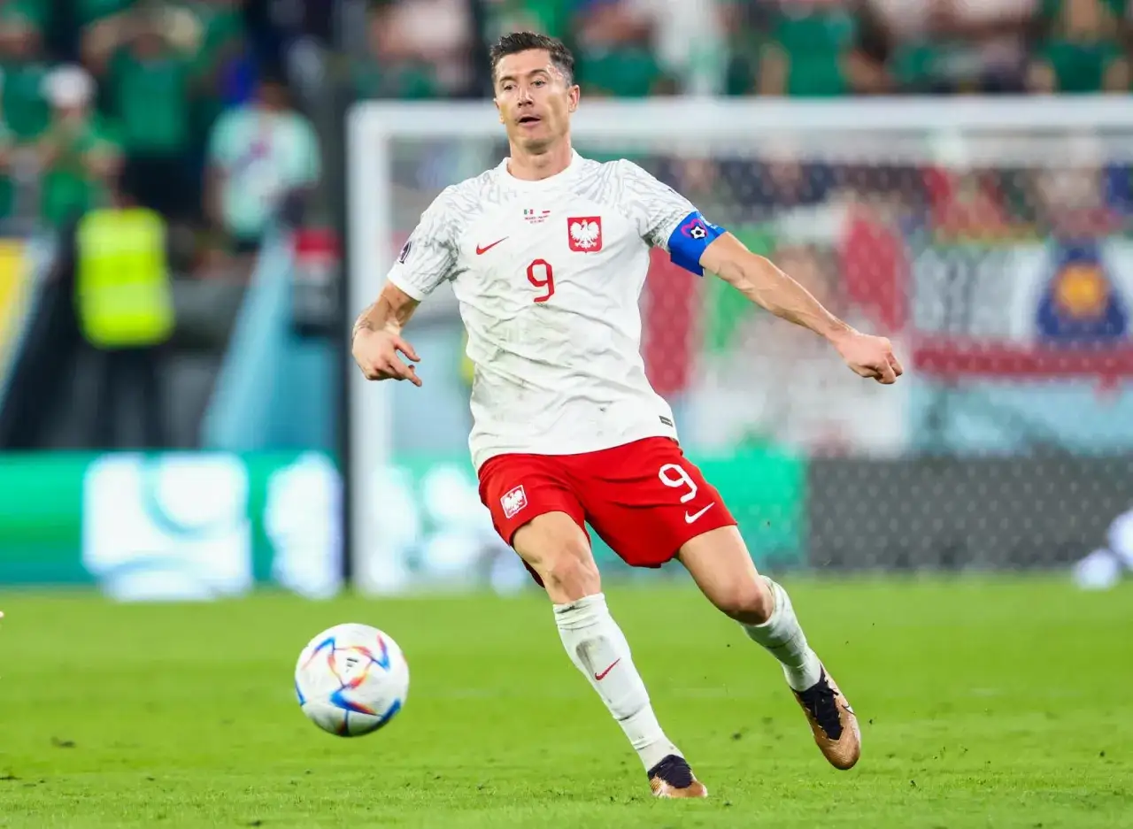 Robert Lewandowski w akcji, z piłką przy nodze. Biało-czerwona koszulka z numerem 9 i godłem Polski. Wynik Polska jest w jego rękach!
