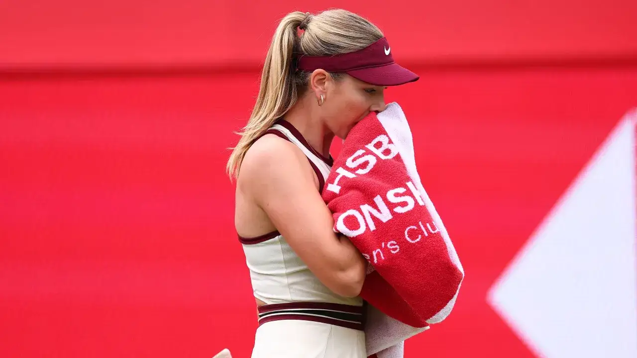 Katie Boulter z ręcznikiem na korcie, w tle czerwony baner.