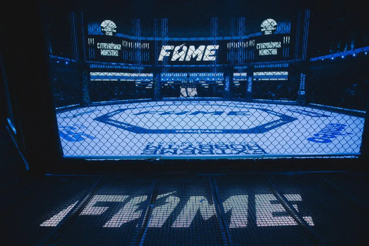 Pusta klatka FAME MMA w niebieskim świetle, gotowa na emocjonujące starcia.