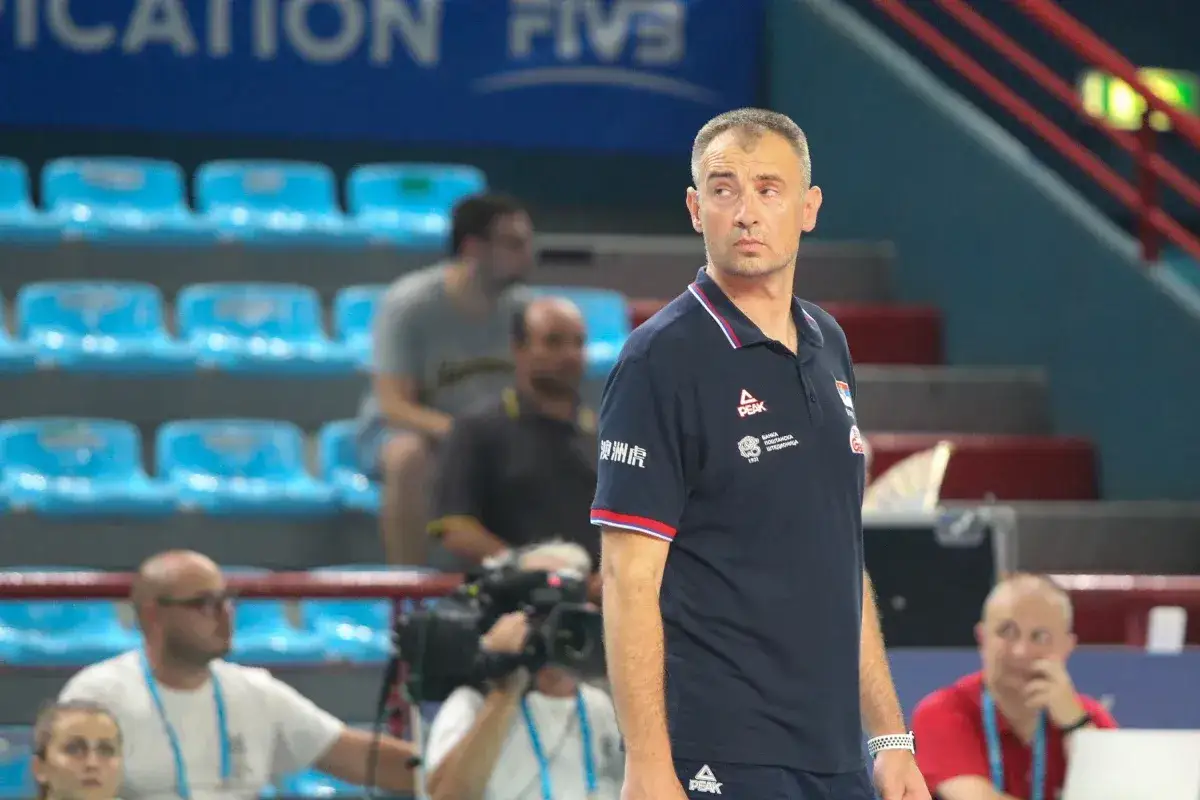 Trener siatkówki Nikola Grbić w koszulce z logo Peak, obserwuje mecz z ławki.