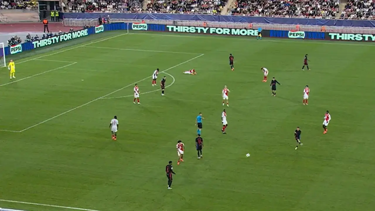 Piłkarze AS Monaco FC w akcji podczas rozgrywek. Na boisku widać zawodników w białych i czerwonych strojach, walczących o piłkę.