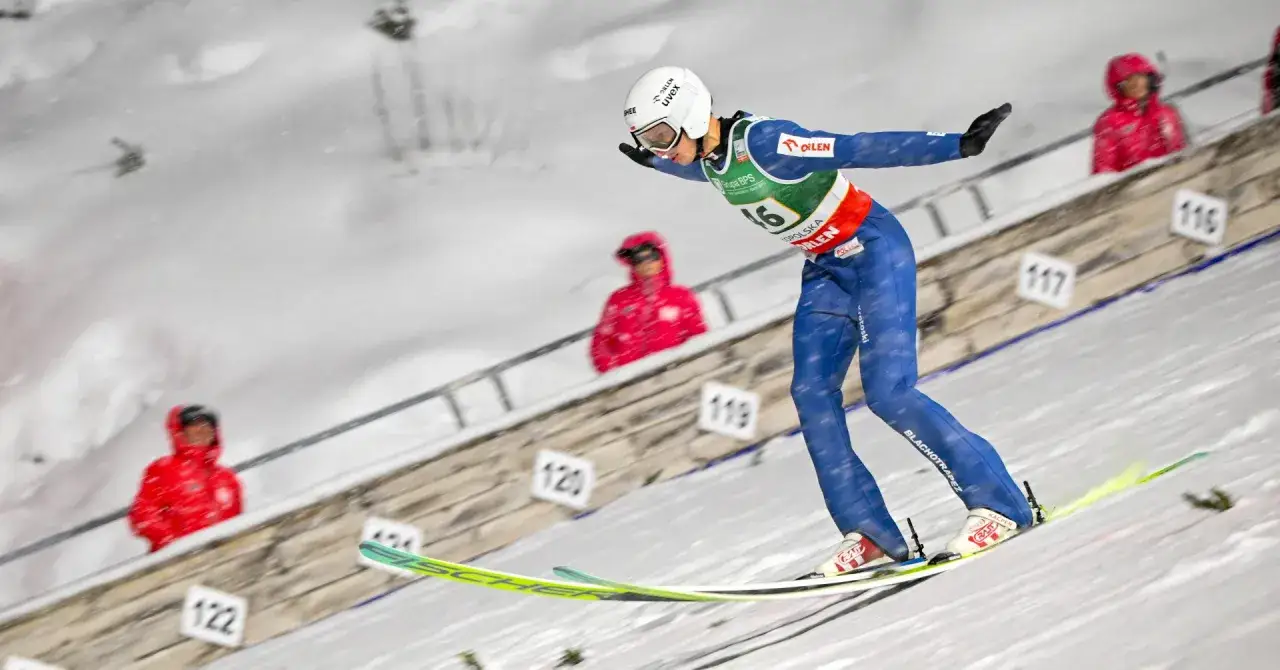 Młody skoczek narciarski w niebieskim kombinezonie szykuje się do skoku. To może być jego start na mistrzostwa świata juniorów w skokach narciarskich 2026.