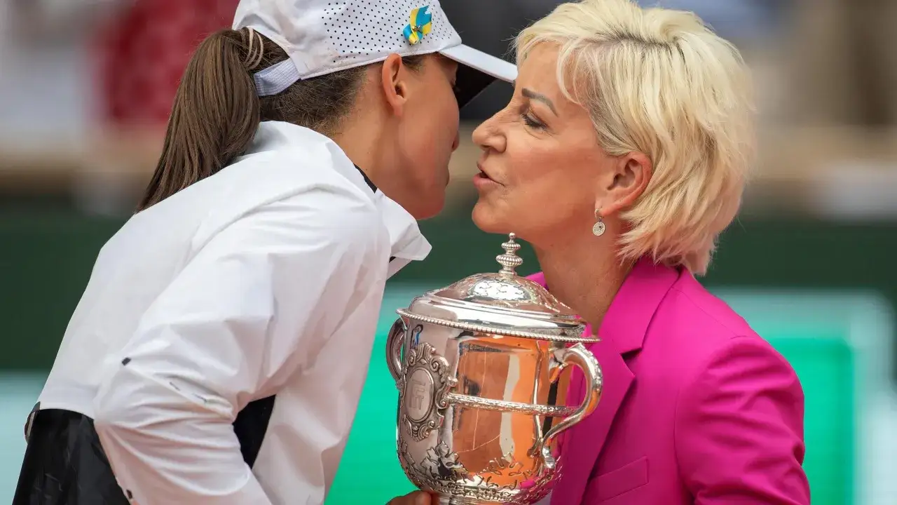 Dwie kobiety całują się nad pucharem Roland Garros. Jedna z nich ma na czapce przypinkę w barwach Ukrainy.